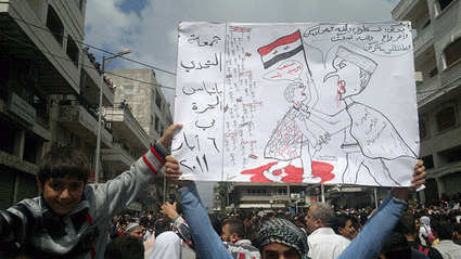 A man holds up a political cartoon at a Syrian protest in May 2011