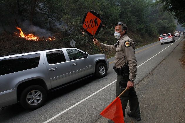 A park ranger directs traffic along Highway 1 as the Big Sur fire burns nearby.