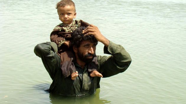 A man in the water carrying a child on his shoulders